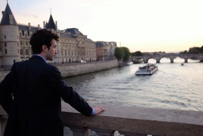 Rear view of businessman standing on bridge over seine river by conciergerie