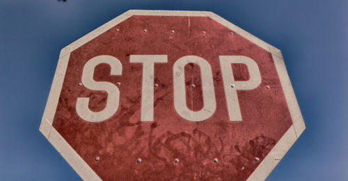 Close-up of road sign against blue sky