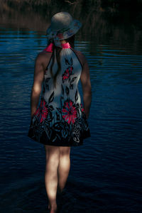 Rear view of shirtless woman standing in lake