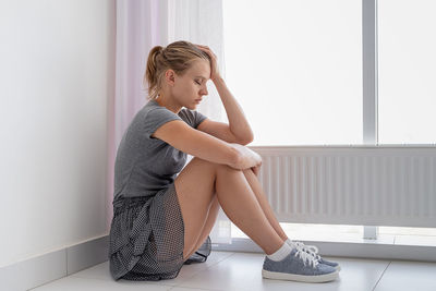 Mental health. depressed young woman in gray shirt and skirt sitting on the floor