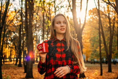 Portrait of young woman standing in forest during autumn