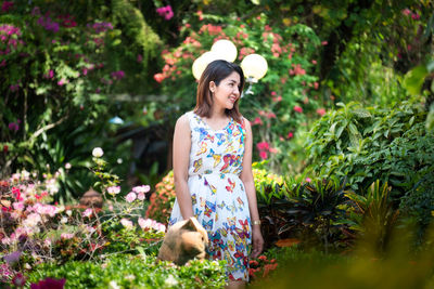 Young woman standing by flowering plants