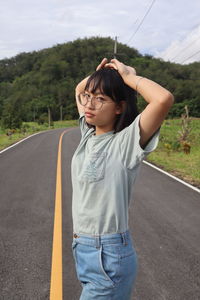 Full length of teenage girl standing by road against sky