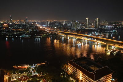 High angle view of illuminated buildings by river at night