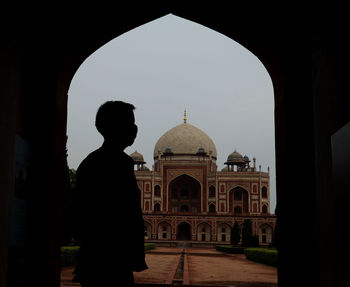 Silhouette of man standing in front of historic building