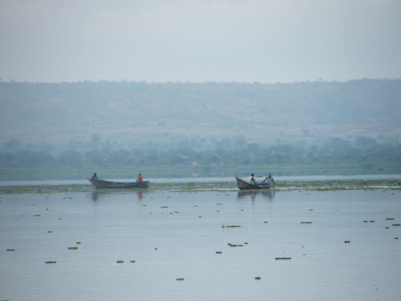 PEOPLE IN BOAT ON LAKE AGAINST SKY