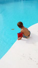 High angle view of boy sitting at poolside