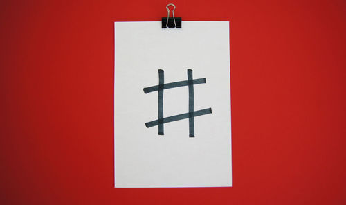 Close-up of arrow sign against red wall