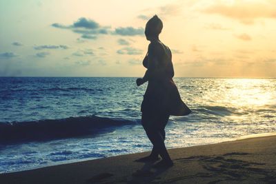 Silhouette woman standing on beach during sunset