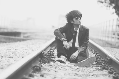 Businessman sitting on railroad track