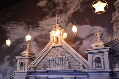 Low angle view of illuminated street light by building against sky