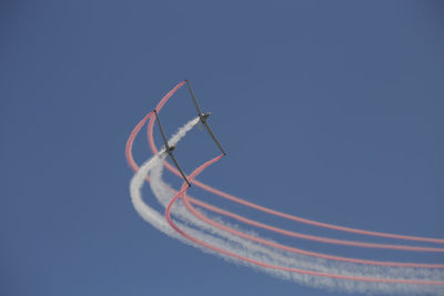 Low angle view of airplane flying against clear blue sky