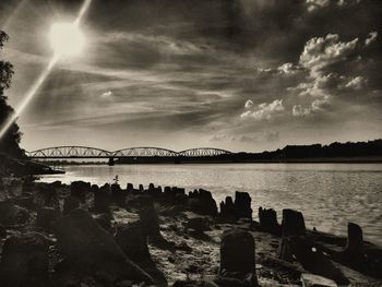 Bridge over river against cloudy sky