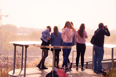 Friends at observation point against sky during sunset