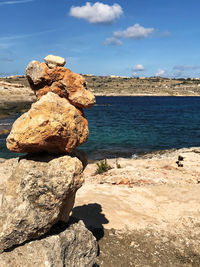 Rock formation on beach against sky