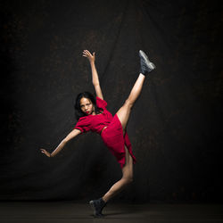 Portrait of woman with arms raised against black background