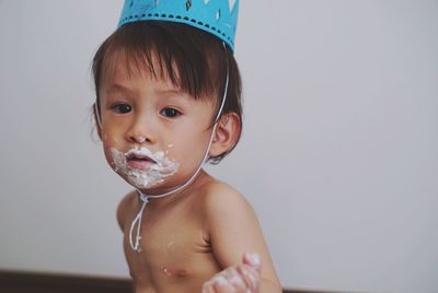 Close-up of cute boy blowing bubbles against white background