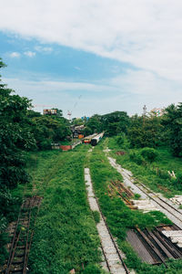 Panoramic view of railroad tracks amidst trees and buildings against sky