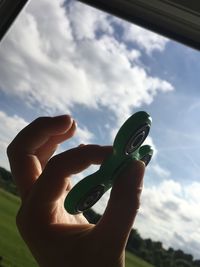 Low angle view of hand holding leaf against sky