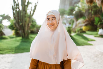 Portrait of young woman standing against trees