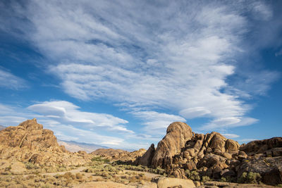 Rock formations on ldesert andscape against sky with lenticular clouds