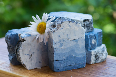 Blue handmade soap with chamomile flowers on a green background