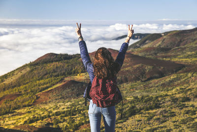 Rear view of woman standing on mountain against sky