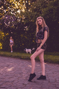 Portrait of beautiful woman standing on footpath with friend in background