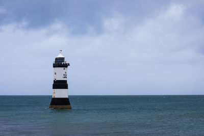 Lighthouse by sea against sky