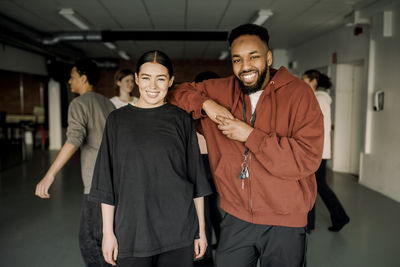 Portrait of smiling male and female teacher standing in dance studio at high school