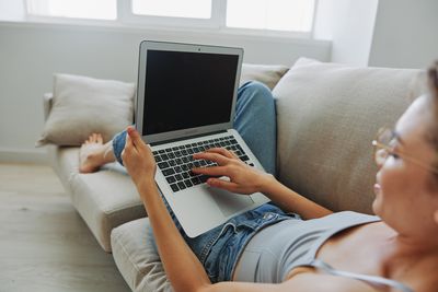 Midsection of woman using laptop at home