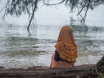 Rear view of woman standing on riverbank