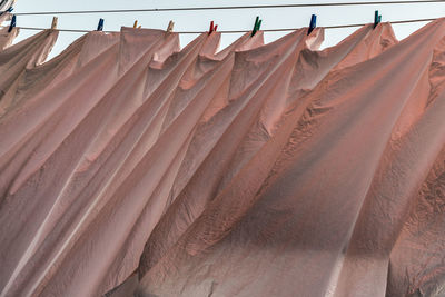 Low angle view of pink sheets hung to dry in a breeze on clothesline