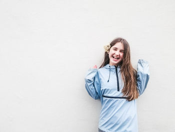 Portrait of young woman standing against white background