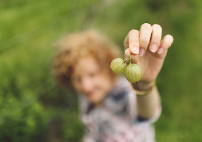 High angle view of woman showing two gooseberries