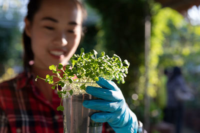 Young woman holding plants in nursery