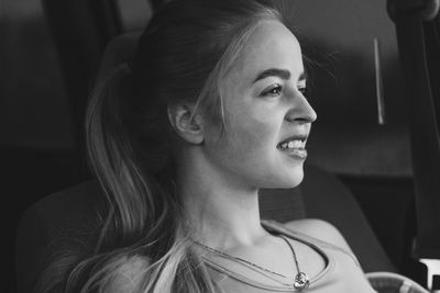 Close-up of thoughtful young woman smiling while traveling in car