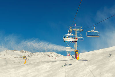 Overhead cable car against snowcapped mountains against sky