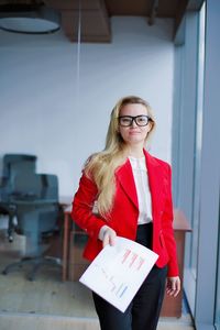 Portrait of a young woman standing against wall