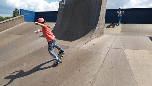 Siblings skateboarding in park