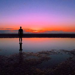 Silhouette of people standing on beach at sunset