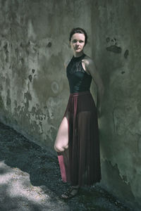 Portrait of young woman standing against wall