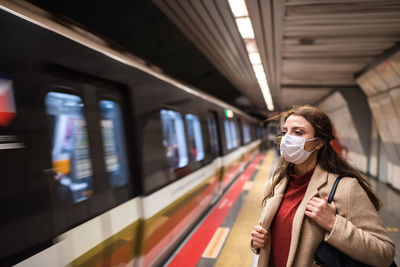 Woman wearing mask standing on railroad station platform