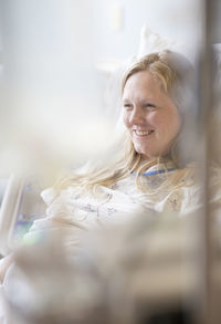 Smiling woman looking away on bed at hospital