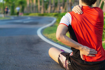 Rear view of man sitting on road