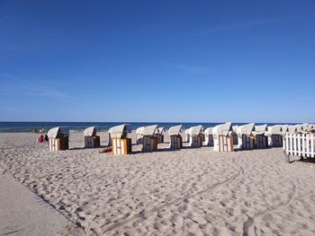 Hooded chairs at beach against blue sky