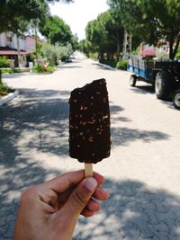 Close-up of hand holding ice cream cone on road