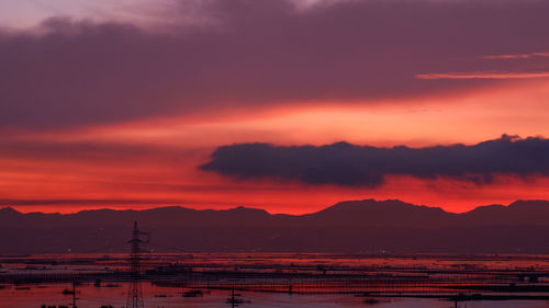 Scenic view of dramatic sky over silhouette landscape during sunrise