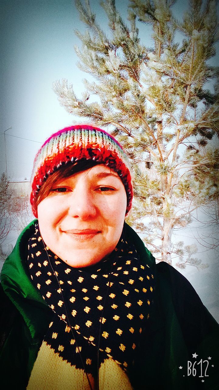 PORTRAIT OF YOUNG WOMAN STANDING AGAINST TREES