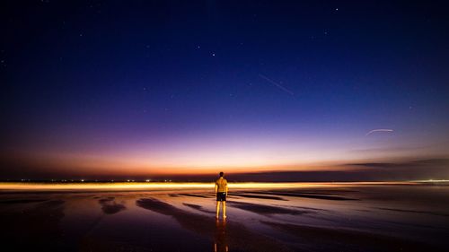 Rear view of man standing against sky at beach